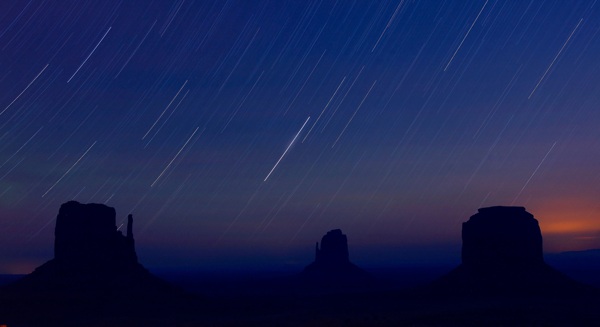 靜謐夜空星星和地平線上幾座獨(dú)特的巖石山峰