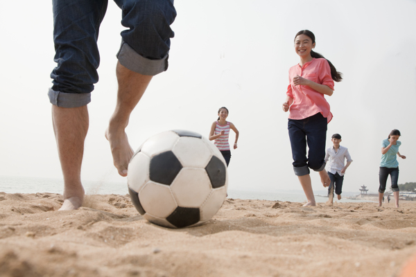 沙滩上踢足球的年轻人图片