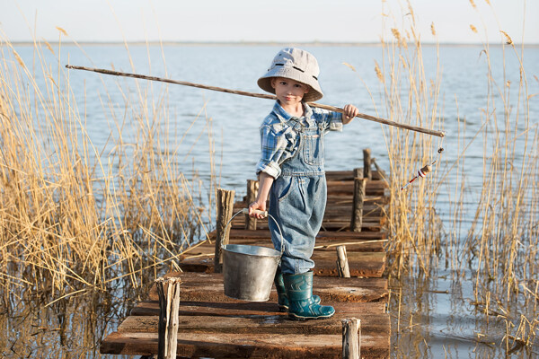 湖边提桶钓鱼的小男孩