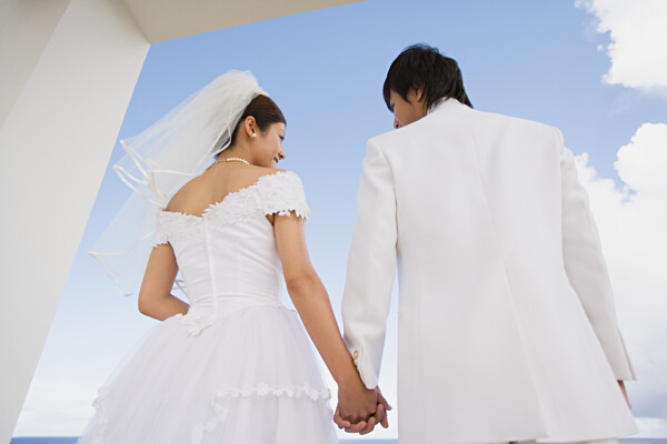 穿着婚纱礼服牵着手的情侣背影图片图片