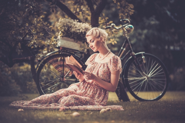 树下草地上的看书美女和自行车图片