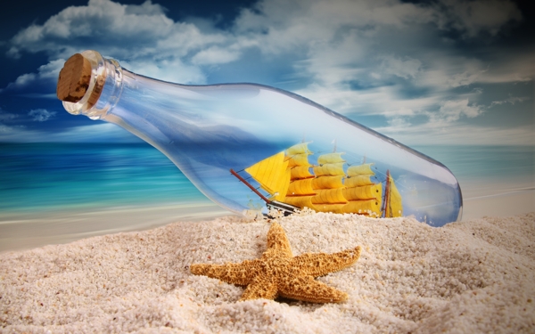 在蓝色天空下沙滩上的一个漂流瓶的特写