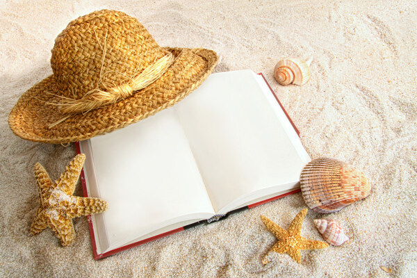 沙子上的书本与帽子图片