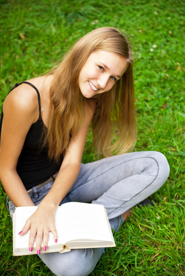 坐在草地上看书的外国女孩图片